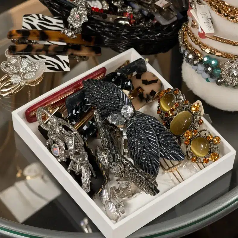 Crystal hair clips and stacked bracelets on a glass display table